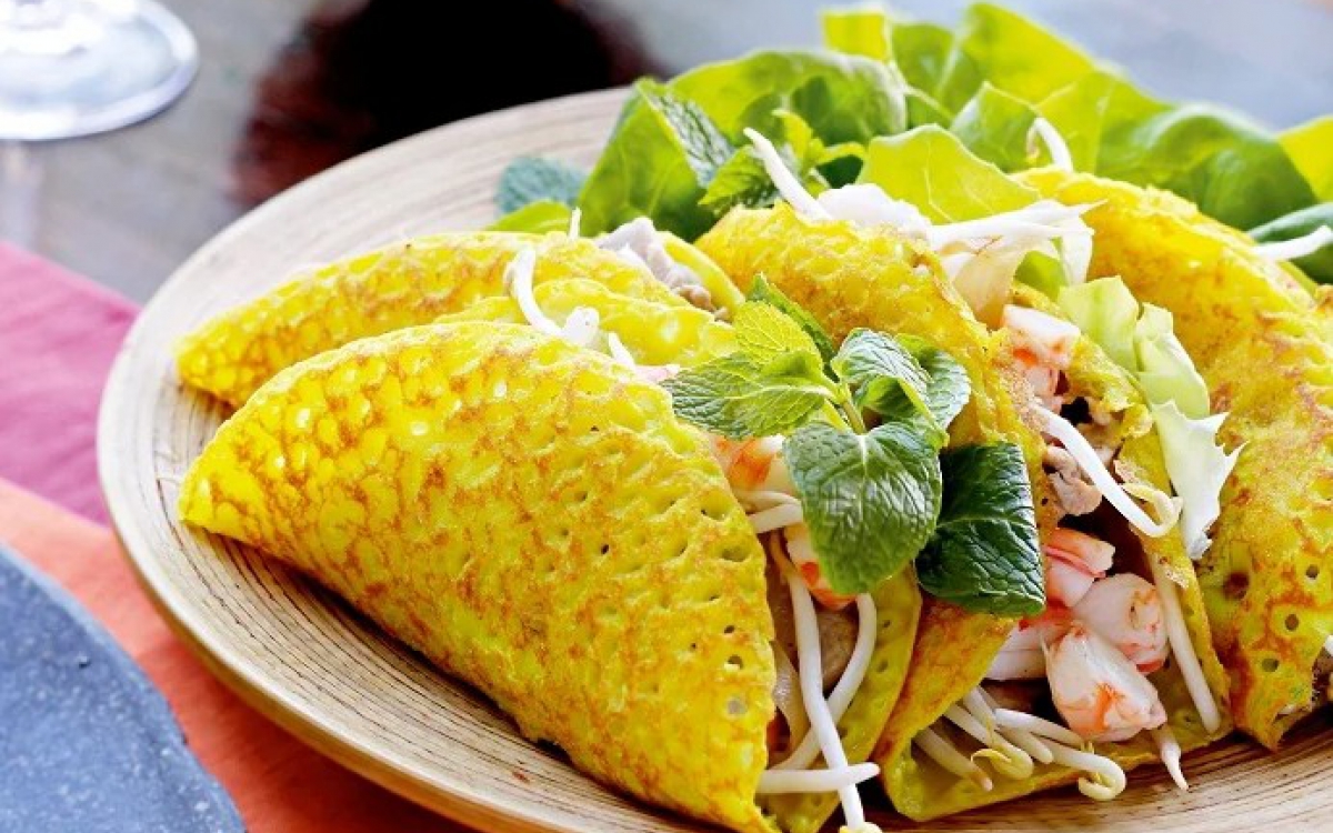 A Bánh xèo giòn rụm với nhân tôm thịt, giá đỗ, ăn kèm rau sống và nước mắm chua 